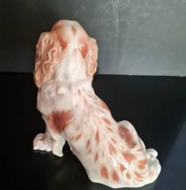 Cane  porcellana di Meissen  seduto con mantello marrone e bianco, testa girata . Marchio di spade i