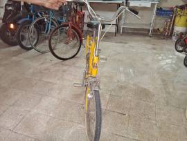 Bicicletta vintage gialla con telaio in metallo, sellino nero e portapacchi posteriore. Ruote di dim